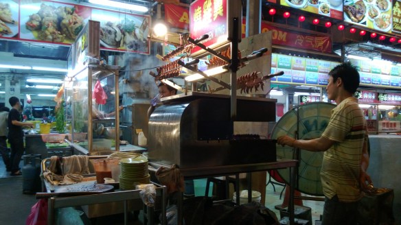 A cook at the hawker street stall, barbecuing something. Probably chicken feet, as those seemed to be pretty popular there.